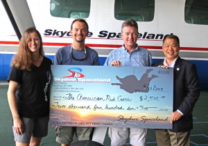 Skydive Spaceland marketing director Christy West, general manager Jason Hyder, and owner Steve Boyd present Dave Dunn of the Red Cross with a check for $2,510 to aid tornado victims in Oklahoma.